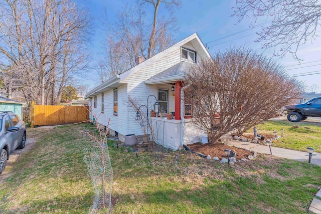 view of front facade with a front lawn, fence, covered porch, and a chimney