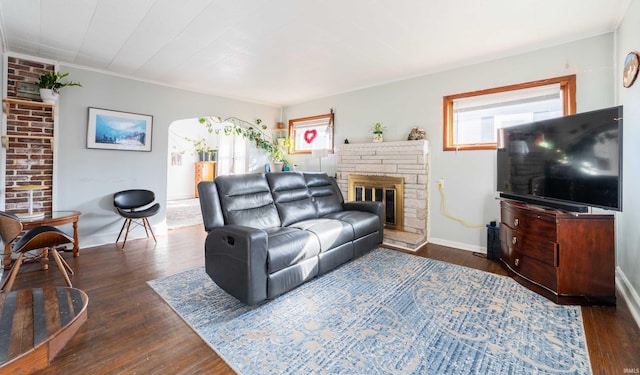 living area with baseboards, dark wood-style floors, a fireplace, and crown molding