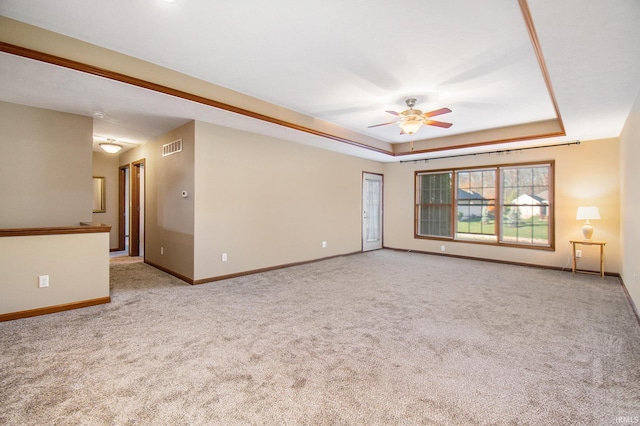 empty room featuring carpet, baseboards, visible vents, ceiling fan, and a raised ceiling