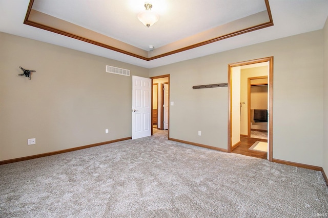 unfurnished bedroom featuring a tray ceiling, baseboards, and visible vents