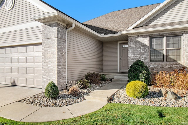 entrance to property with a garage, brick siding, and a shingled roof