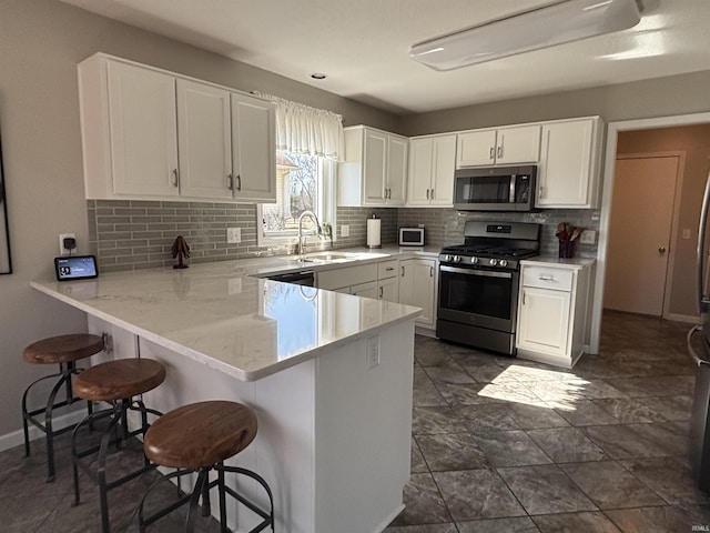 kitchen with a sink, a kitchen bar, appliances with stainless steel finishes, and white cabinets