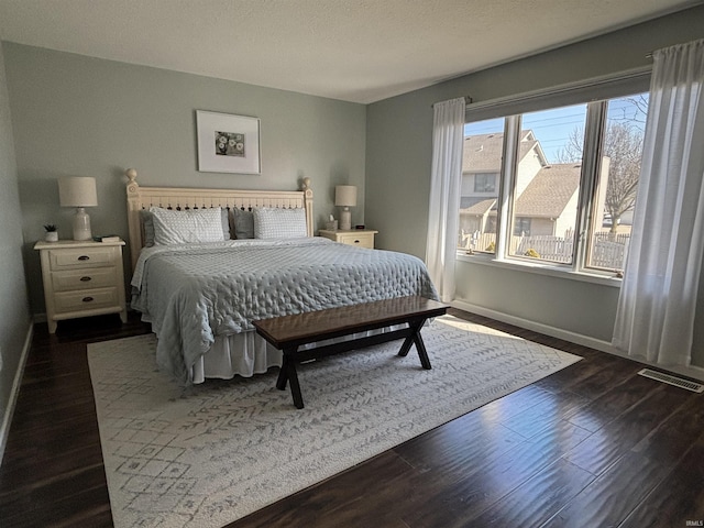 bedroom featuring visible vents, baseboards, and dark wood-style floors