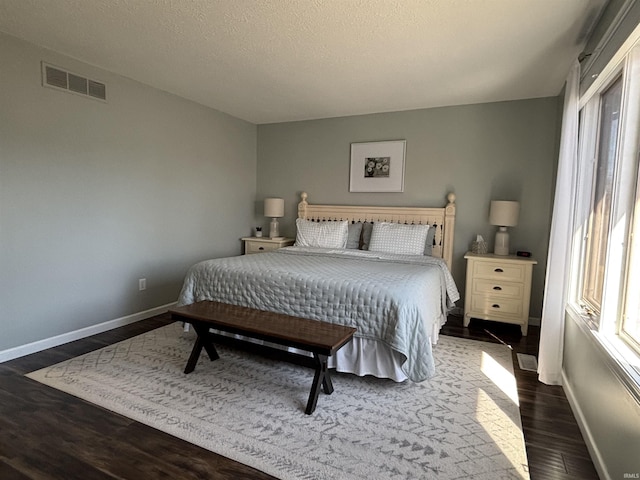 bedroom featuring visible vents, a textured ceiling, baseboards, and dark wood-style flooring