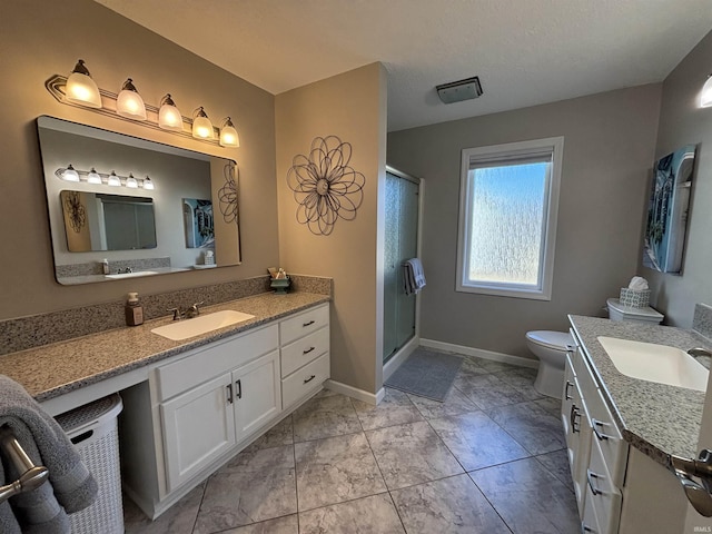 bathroom featuring a sink, baseboards, two vanities, and a stall shower