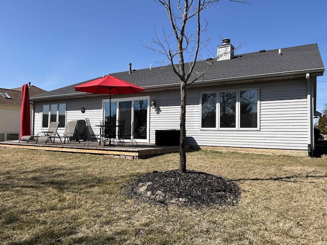 rear view of property featuring a patio area, a lawn, a chimney, and a shingled roof