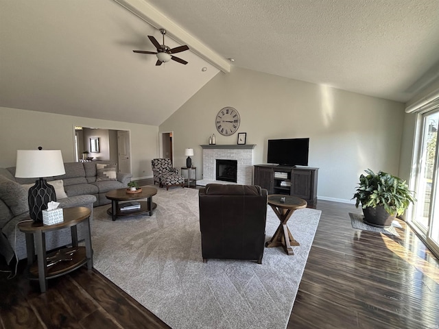 living area featuring a ceiling fan, dark wood-style floors, lofted ceiling with beams, a fireplace, and a textured ceiling