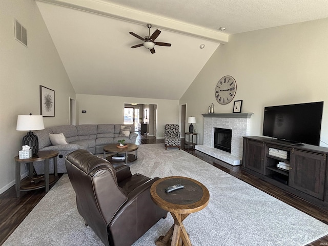 living room with visible vents, a brick fireplace, vaulted ceiling with beams, dark wood-type flooring, and ceiling fan