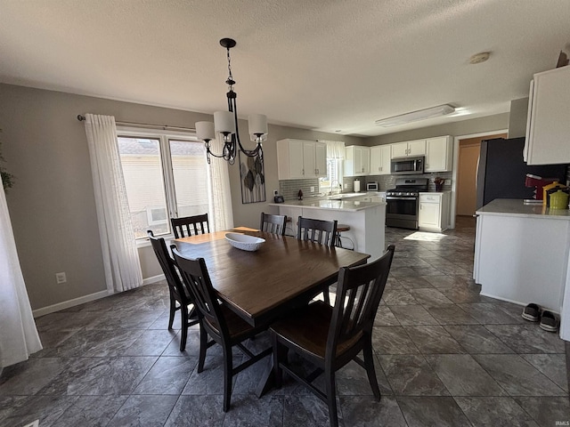 dining room with a notable chandelier, baseboards, and a textured ceiling