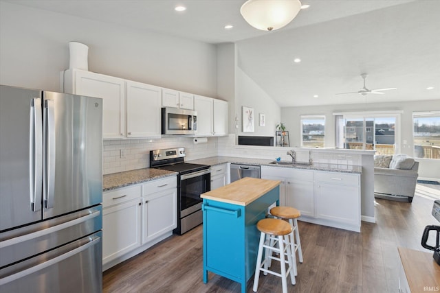 kitchen with white cabinets, appliances with stainless steel finishes, a peninsula, and a sink