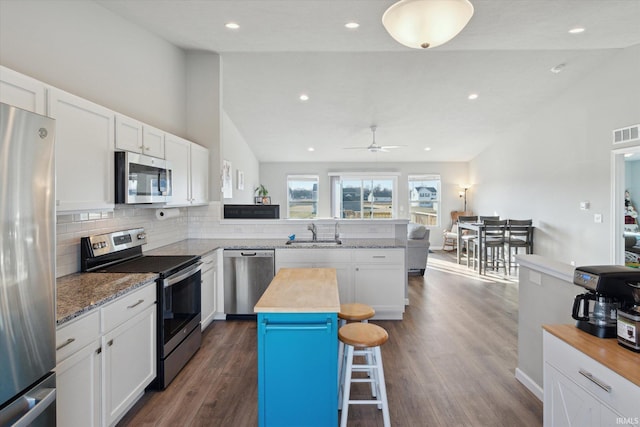 kitchen with butcher block countertops, decorative backsplash, a peninsula, stainless steel appliances, and white cabinetry