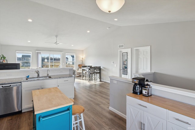 kitchen featuring visible vents, a sink, wood counters, stainless steel dishwasher, and white cabinets