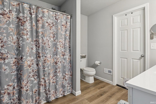 bathroom with visible vents, baseboards, toilet, wood finished floors, and vanity