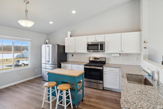 kitchen featuring butcher block countertops, appliances with stainless steel finishes, white cabinetry, and a sink