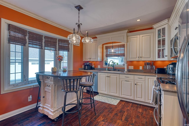 kitchen with dark wood-style floors, a sink, ornamental molding, stainless steel appliances, and white cabinetry