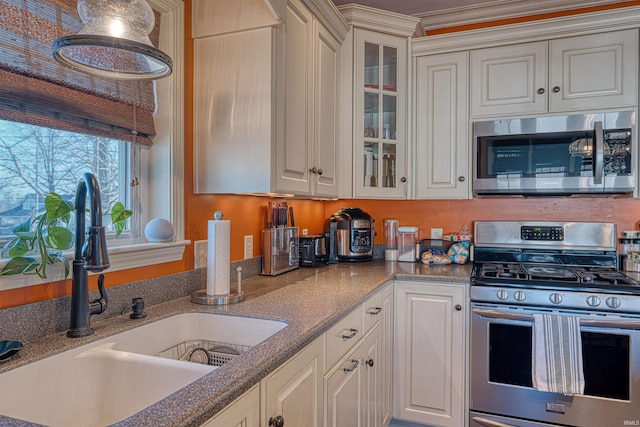 kitchen featuring appliances with stainless steel finishes, dark stone counters, glass insert cabinets, and a sink