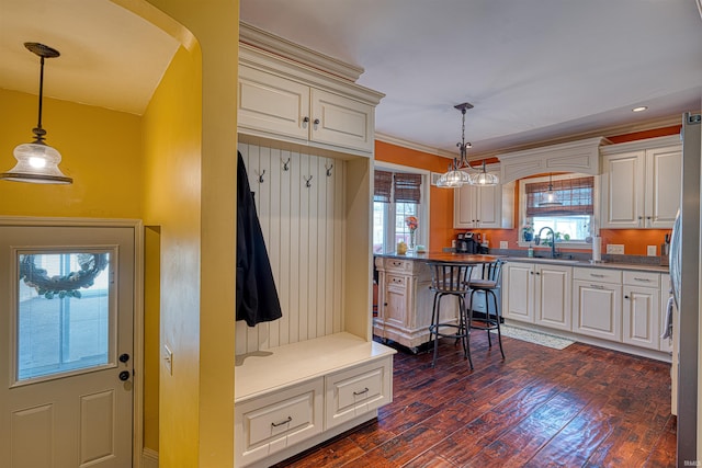 mudroom with crown molding, dark wood-type flooring, recessed lighting, arched walkways, and a sink