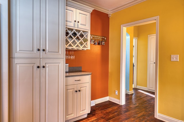 hallway with dark wood-type flooring, baseboards, and ornamental molding