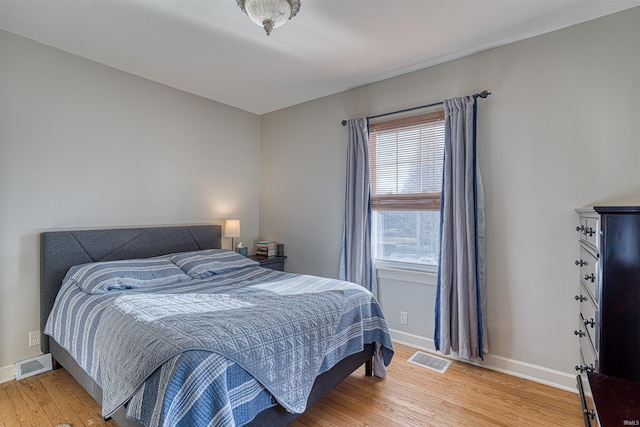 bedroom with baseboards, visible vents, and light wood finished floors