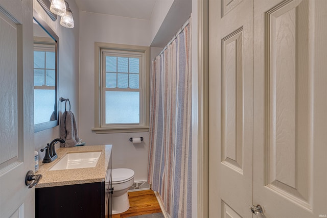 full bathroom featuring plenty of natural light, toilet, vanity, and wood finished floors