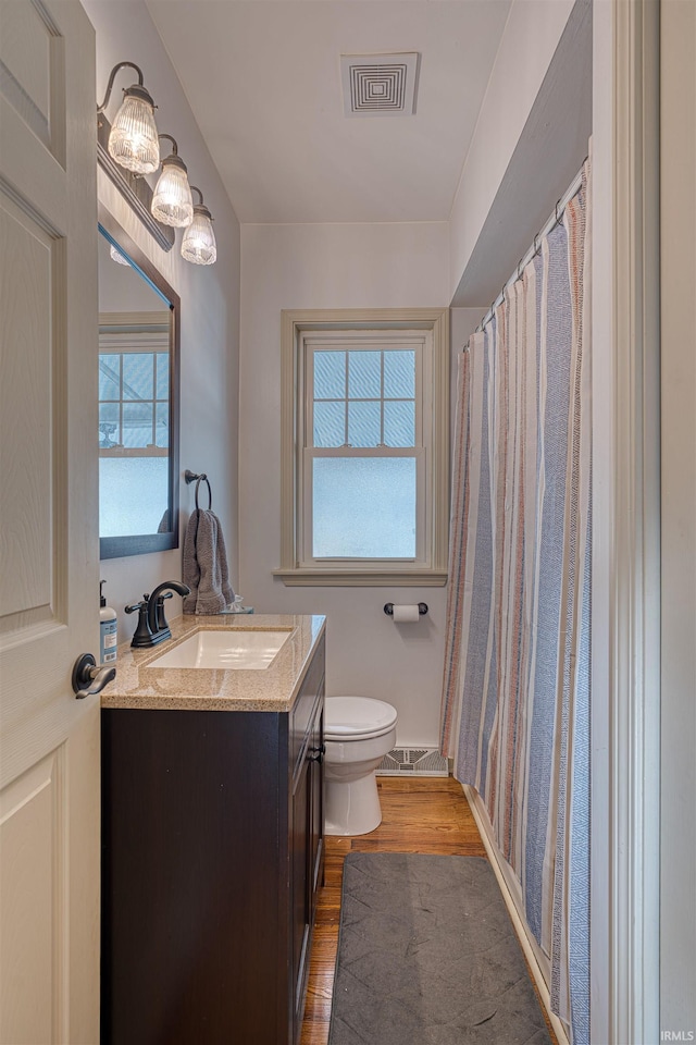 full bathroom with vanity, toilet, wood finished floors, and visible vents