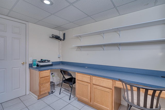 office area featuring light tile patterned flooring, a drop ceiling, and built in study area