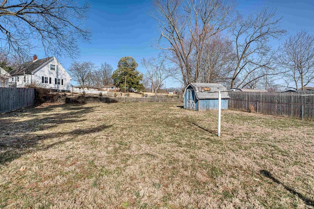 view of yard with a storage shed, a fenced backyard, and an outbuilding