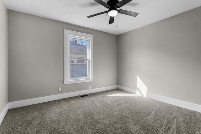 carpeted spare room with visible vents, baseboards, and ceiling fan