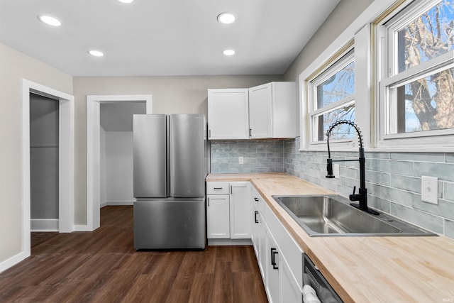 kitchen with a sink, dark wood finished floors, white cabinetry, freestanding refrigerator, and butcher block counters