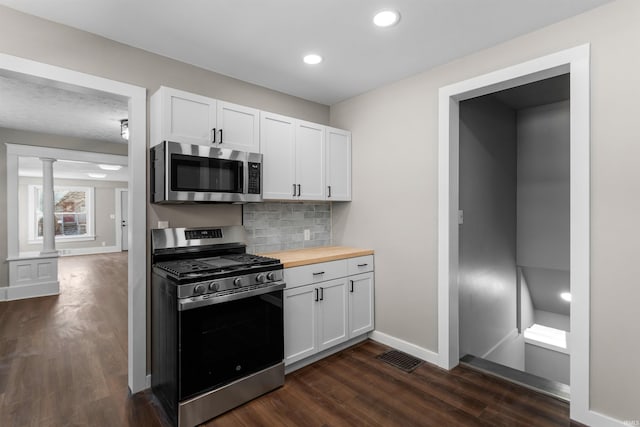 kitchen with dark wood-style flooring, butcher block countertops, stainless steel appliances, white cabinetry, and backsplash