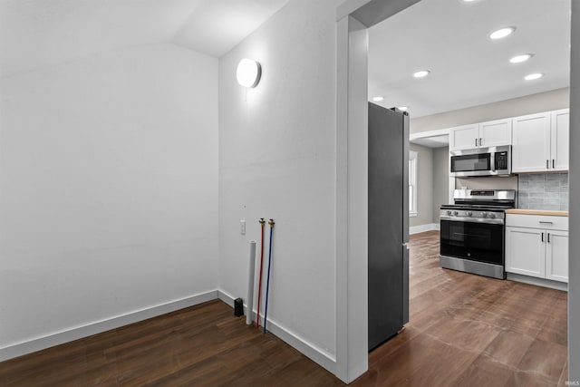 kitchen featuring dark wood-type flooring, tasteful backsplash, appliances with stainless steel finishes, and white cabinetry