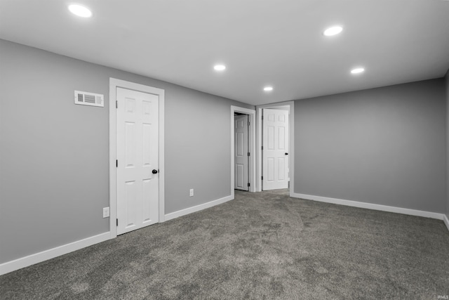 finished below grade area featuring recessed lighting, baseboards, visible vents, and dark carpet