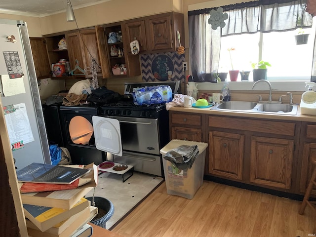 kitchen with brown cabinets, light wood-style flooring, a sink, open shelves, and stainless steel appliances