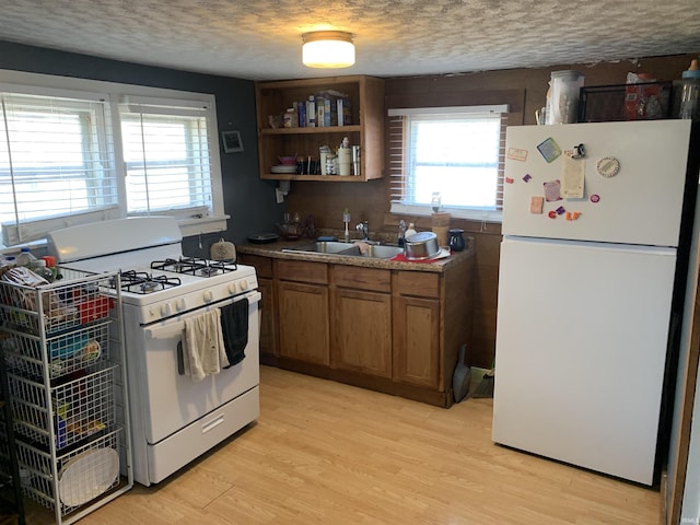 kitchen featuring a textured ceiling, white appliances, light wood-type flooring, and a sink