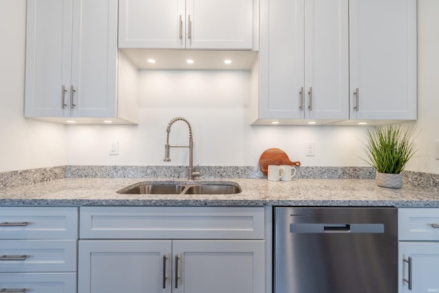 kitchen featuring light stone counters, white cabinets, dishwasher, and a sink