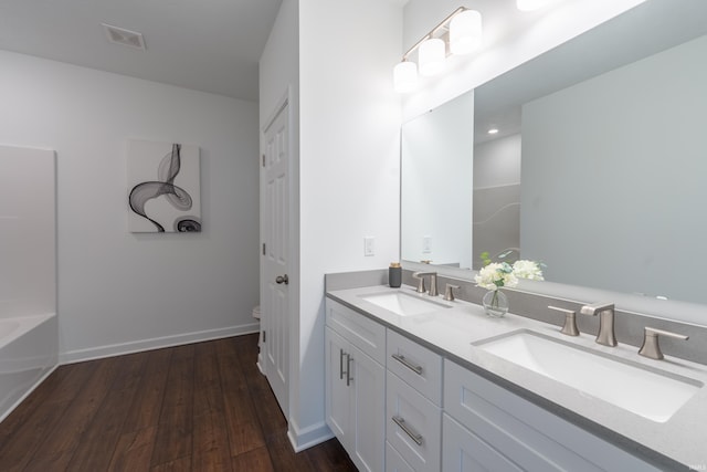 bathroom with a sink, toilet, wood finished floors, and double vanity