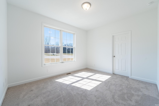 carpeted spare room featuring visible vents and baseboards