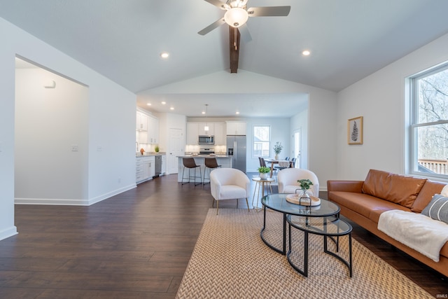 living area with dark wood finished floors, plenty of natural light, vaulted ceiling with beams, and ceiling fan