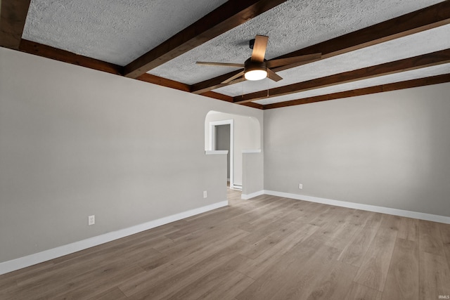 spare room with beam ceiling, wood finished floors, a ceiling fan, and a textured ceiling