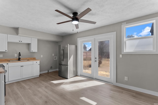 kitchen featuring light wood-type flooring, a ceiling fan, a sink, freestanding refrigerator, and french doors