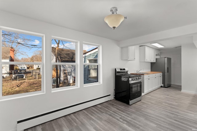 kitchen with a sink, a baseboard heating unit, white cabinetry, light wood-style floors, and appliances with stainless steel finishes