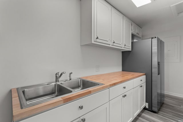 kitchen featuring wooden counters, stainless steel fridge with ice dispenser, wood finished floors, white cabinetry, and a sink