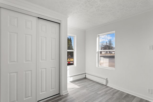 unfurnished bedroom featuring baseboards, wood finished floors, a closet, and a textured ceiling