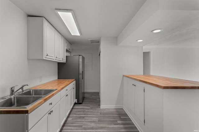 kitchen featuring white cabinetry, butcher block counters, wood finished floors, and a sink