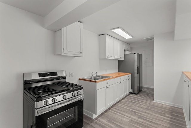 kitchen featuring baseboards, stainless steel appliances, light wood-style floors, white cabinetry, and a sink