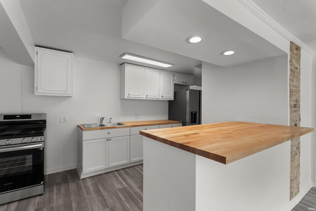 kitchen with white cabinetry, butcher block counters, wood finished floors, and stainless steel appliances