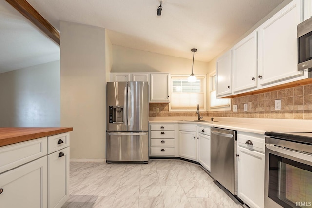 kitchen with a sink, stainless steel appliances, vaulted ceiling, white cabinetry, and marble finish floor