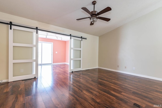 empty room featuring baseboards, a barn door, vaulted ceiling, wood finished floors, and a ceiling fan