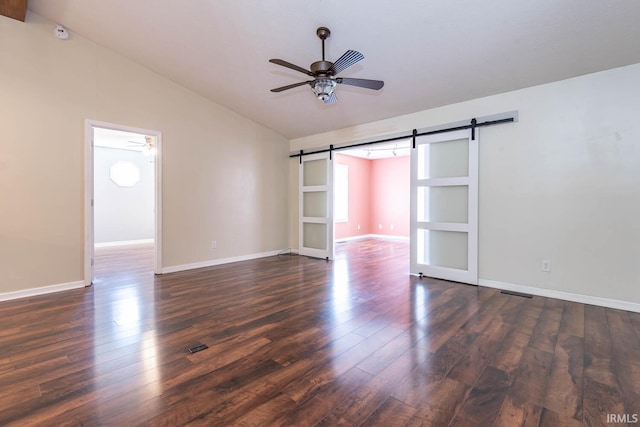 unfurnished room with baseboards, dark wood finished floors, lofted ceiling, a barn door, and a ceiling fan