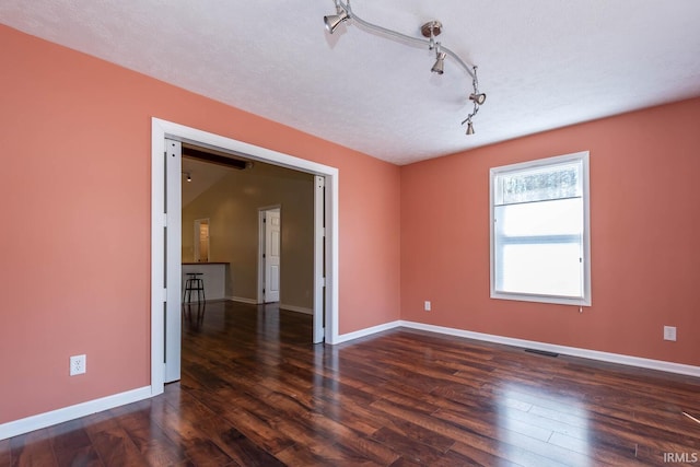 unfurnished room with visible vents, a textured ceiling, baseboards, and wood finished floors